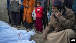 Los niños observan cómo los cuerpos de las víctimas de los ataques nocturnos del ejército israelí en múltiples lugares del centro de la Franja de Gaza son colocados juntos para las oraciones fúnebres, en el Hospital de los Mártires de Al-Aqsa, el viernes 3 de enero de 2025. AP