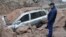 A rescue worker inspects a car caught under a landslide after an earthquake and tsunami hit the northern port of Iquique, Chile, April 2, 2014. 