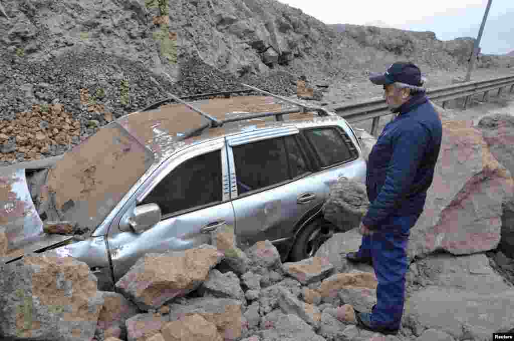 Seorang petugas penyelamat memeriksa mobil yang terperangkap dalam tanah longsor akibat gempa dan tsunami yang melanda pelabuhan Iquique di Chile utara (2/4).