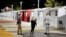 Workers talk to a person who is living at the village (at right) in front of tiny homes for the homeless, February 25, 2021, in the North Hollywood part of Los Angeles. (AP Photo/Marcio Jose Sanchez)