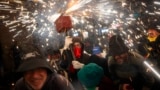 People dance as revelers hold fireworks as they take part in a "Correfoc", or run with fire, party in Barcelona, Spain, Sept. 15, 2024. 