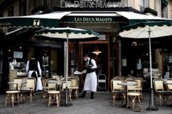 Waiters work at the terrace of a cafe in Paris, on June 15, 2020, one day after French president announced the reopening of dining rooms of Parisian cafes and restaurants, starting today.