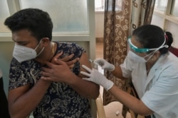 A medical worker inoculates a man with a dose of the COVID-19 coronavirus vaccine in a government hospital in Bangalore, India, on May 7, 2021.