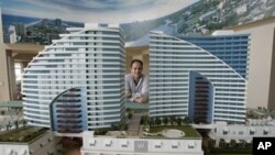 Seorang broker berpose di belakang model sebuah kondo-hotel. Konsep kondo-hotel saat ini semakin populer dalam industri hotel/penginapan. 