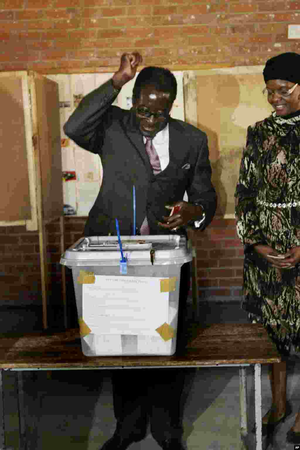 President Robert Mugabe reacts after casting his vote on election day in Harare, Friday, June, 27, 2008. Looking on, is his wife Grace. Zimbabwe is holding a run off election in which Morgan Tsvangirai, the main opposition leader in the country has pulled out citing violence and intimidation