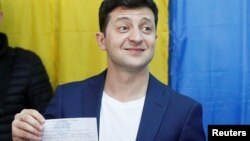 Calon presiden Ukraina Volodymyr Zelenzkiy menunjukkan surat suaranya kepada media di sebuah tempat pemungutan suara dalam pilpres putaran kedua di Kyiv, Ukraina, 21 April 2019.
