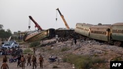 Gerbong-gerbong kereta api diangkat dengan derek di lokasi kecelakaan menyusul tergelincirnya kereta api penumpang di kota Nawabshah, Pakistan Minggu 6 Agustus 2023.