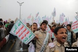 Anak-anak Yaman yang memegang tulisan ikut ambil bagian dalam unjuk rasa Houthi untuk mengecam pelabelan AS terhadap Houthi sebagai kelompok 'Teroris Global', dalam aksi di ibu koya Sanaa, 19 Januari 2024. (Khaled Abdullah/Reuters)