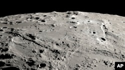 This image provided by NASA shows a view from orbit looking across the surface of the moon, where an ancient asteroid strike carved out a pair of grand canyons on the moon’s far side. (Ernie T. Wright/NASA via AP)