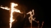 FILE - Members of a white nationalist group burn a swastika and cross outside Atkins, Arkansas, March 9, 2019.