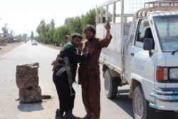 An Afghan policeman searches a man at a road checkpoint during fighting between Afghan security forces and Taliban fighters, on the outskirts of Lashkar Gah, the capital of Helmand province, May 5, 2021.
