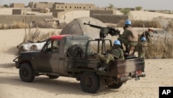 FILE - UN peacekeepers from stand guard during a patrol through a neighborhood on the outskirts of Timbuktu, Mali, March 31, 2014.