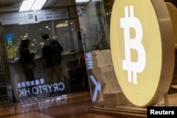 Customers stand at a cryptocurrency exchange store after Bitcoin soars above $100,000, in Hong Kong, China, Dec. 5, 2024.