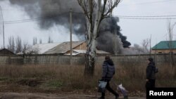 Volodymyr, 61, and Nataliia Bolias, 51, walk past an industrial building that received a missile strike, as Russia's attack on Ukraine continues, during intense shelling on Christmas Day at the frontline in Bakhmut, Ukraine, Dec. 25, 2022.