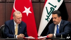 Presiden Turki Recep Tayyip Erdogan, kiri, dan PM Irak Mohammed Shia al-Sudani bertukar perjanjian penandatanganan selama pertemuan mereka di Baghdad, Irak, pada 22 April 2024 (foto: dok). 