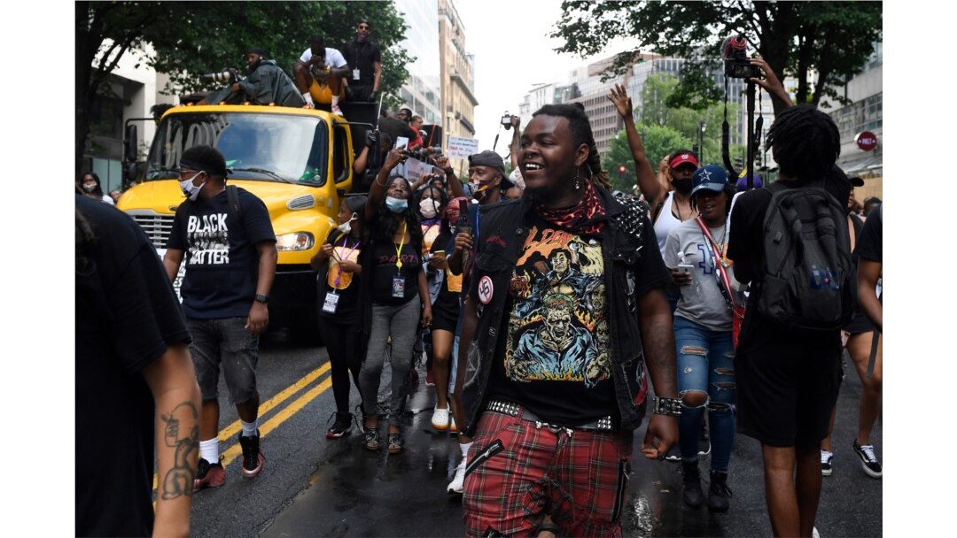 People walk along a flatbed truck with musicians playing Go-go music as they head down a street in Washington, June 19, 2020, to mark Juneteenth. Go-go music is a genre of music that originated in Washington.