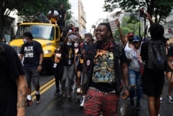 People walk along a flatbed truck with musicians playing Go-go music as they head down a street in Washington, June 19, 2020, to mark Juneteenth. Go-go music is a genre of music that originated in Washington.