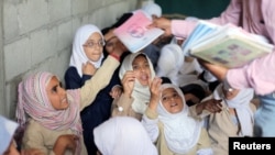 Students receive books in their class at the teacher's house, who turned it into a makeshift free school that hosts 700 students, in Taiz, Yemen, Oct. 18, 2018. 