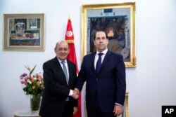 Tunisian Prime minister Youssef Chahed, right, shakes hands with French Foreign Minister Jean-Yves Le Drian, in Tunis, Jan. 9, 2020.