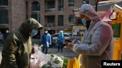 신종 코로나바이러스 감염증(COVID-19) 발원지인 중국 후베이성 우한에서 마스크를 착용한 시민이 단체주문한 채소를 받고 있다.