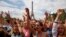 Children gesture during a live music concert of the Vacation for Everyone day event at the Eiffel Tower in Paris, France, Aug. 19, 2015. 