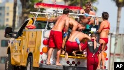 Salvavidas ayudan a una persona que estaba en el agua cuando cayó el rayo el domingo por la tarde en la playa de Venice, en Los Ángeles.