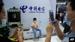 Visitors take photos near an antique telephone booth and a child at the China Telecom stand during the China International Fair for Trade in Services (CIFTIS) in Beijing, China on Sept. 5, 2021.