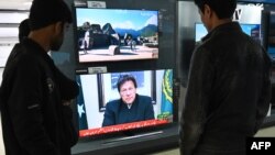 FILE - People watch Pakistani Prime Minister Imran Khan address the nation on TV following the Feb. 14 suicide bombing in Indian-administered Kashmir, in Islamabad, Feb. 19, 2019.