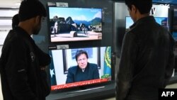 FILE - People watch Pakistani Prime Minister Imran Khan address the nation on TV following the Feb. 14 suicide bombing in Indian-administered Kashmir, in Islamabad, Feb. 19, 2019.