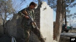 FILE - An Afghan security officer steps on wreckage of a suicide attacker's car near U.S. Forward Operating Base Chapman in Khost province, Afghanistan, Jan. 19, 2009.