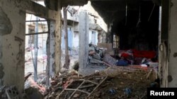 A man rests inside a building destroyed during recent fighting in Yemen's southwestern city of Taiz, March 14, 2016. The war has displaced on in 10 Yemenis, many of whom are living with host families.