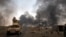 FILE - Iraqi security forces patrol as smoke rises from burning oil wells in Qayara, south of Mosul, Iraq, Aug. 31, 2016. As Iraqi and coalition forces prepare to move on Mosul, IS fighters reportedly are digging trenches around the city which they plan t
