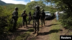 FILE - Soldiers guard an area where a mass grave was found, in Colonia las Parotas on the outskirts of Iguala, in Guerrero, Mexico.