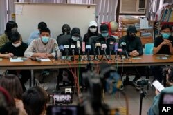 Relatives of a dozen Hong Kong citizens who have been detained in mainland China, wearing caps or hoods, attend a press conference in Hong Kong, Dec. 12, 2020.