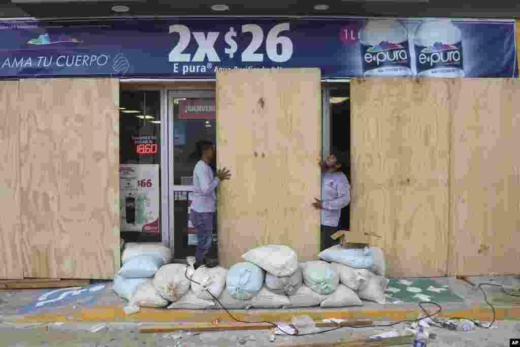 Los locales comerciales buscaron proteger sus negocios de los fuertes vientos, cubriendo sus fachadas con tablones de madera.&nbsp;En Cancún, se vio a pescadores asegurando sus botes en previsión del huracán.