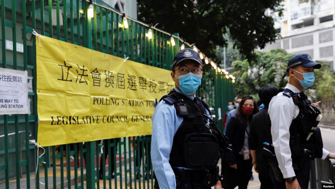 Petugas polisi tampak berjaga di luar tempat pemungutan suara di Hong Kong pada pemilu legislatif yang digelara pada 19 Desember 2021. (Foto: Reuters/Tyrone Siu)