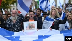 A participant displays a photo of a family held hostage by Palestinian militants in the Gaza Strip, during a rally in front of the Brandenburg Gate in central Berlin on October 6, 2024, ahead of the one-year anniversary of the October 7 attack on Israel b