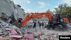 Warga mencari korban selamat di antara reruntuhan gedung di kota pantai Izmir, pasca gempa kuat melanda kawasan Laut Aegea, Turki tenggara hari Jumat (30/10). 
