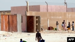 Quelques personnes devant une ancienne école appelée par les locaux "Guantanamito", transformée en 2006 en centre de détention pour immigrants clandestins dans la ville portuaire de Nouadhibou, Mauritanie, 9 octobre 2008.