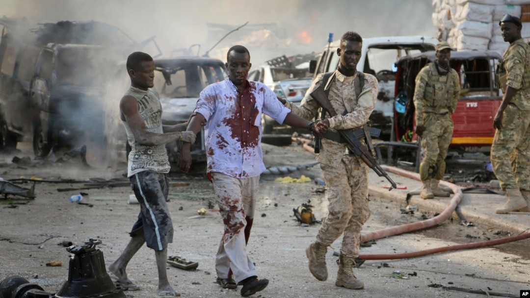 Seorang tentara Somalia menolong seorang warga sipil yang terluka dalam sebuah ledakan di Ibu Kota Mogadishu, 14 Oktober 2017. 