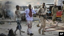 A Somali soldier helps a civilian who was wounded in a blast in the capital of Mogadishu, Somalia, Saturday, Oct. 14, 2017. 