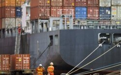 FILE - Workers rest near a loaded cargo ship at the Tianjin port in China.