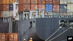 Workers rest near a loaded cargo ship at the Tianjin port in China. A Chinese state news agency said the country's trade surplus in January narrowed sharply to $6.5 billion, February 14, 2011