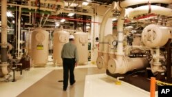 FILE - A worker walks past equipment in the turbine building at the Oyster Creek nuclear plant in Lacey Township, N.J., Feb. 25, 2010.