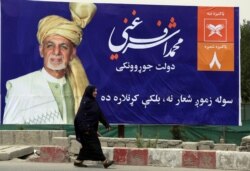 An Afghan woman walks past an election poster of current president and presidential candidate Ashraf Ghani during the first day of campaigning in Kabul, Afghanistan, July 28, 2019.