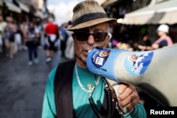 A supporter of former Israeli Prime Minister Benjamin Netanyahu holds a megaphone as he campaigns at Mahane Yehuda market, a day before the Nov. 1 general election in Jerusalem, Oct. 31, 2022.