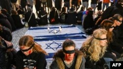 FILE - People wearing blindfolds and with hands tied, as a representation of the kidnapped hostages in Gaza, take part in vigil in Prague on November 7, 2023.