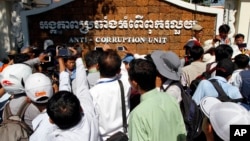 Journalists try to interview a leader of Cambodian activists during a march in front of the Anti-Corruption Unit, in Phnom Penh, Cambodia, Thursday, May 29, 2014. (AP Photo/Heng Sinith)