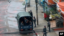 FILE - Police security forces stand by inside a police vehicle and on the sidewalk of Hledan Road in Kamayut township in Yangon, Myanmar, April 16, 2021.