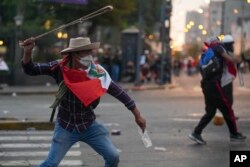 Para pengunjuk rasa anti-pemerintah bentrok dengan polisi di Lima, Peru, Sabtu, 28 Januari 2023, di tengah krisis politik setelah penggulingan Presiden Pedro Castillo pada Desember. (AP/Guadalupe Pardo)